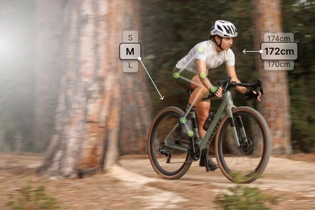Radfahrerin mit Helm auf einem Mountainbike in einem Wald, umgeben von grafischen Elementen zur Körpervermessung und Größenangaben.