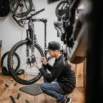 Mitarbeiter Jacob repariert Mountainbike, welches am Montageständer hängt